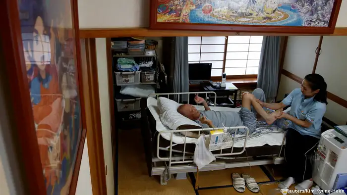 A massage therapist and Mitsuru Niinuma in his bedroom (Reuters/Kim Kyung-Hoon)