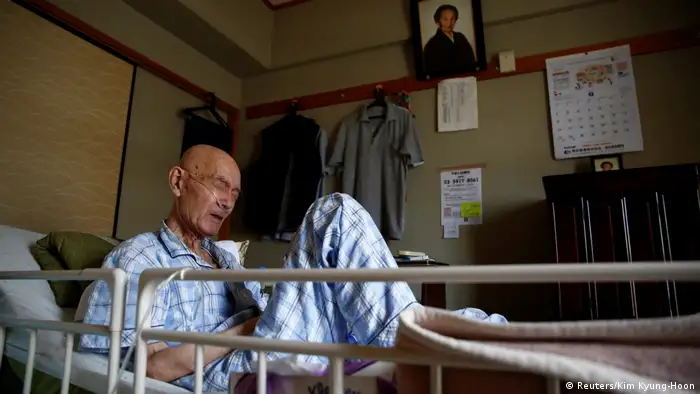 Der krebskranke Yasuhiro Sato in seinem Krankenbett, an der Wand hinter ihm ein Portrait seiner verstorbenen Großmutter (Reuters/Kim Kyung-Hoon)