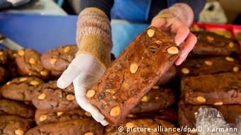 A vendor shows off dessert bread with dried fruit at the Nuremberg Christmas market