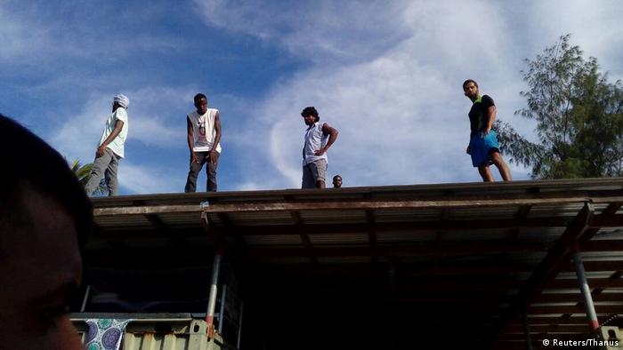 Four asylum seekers climb on top of a building in order to avoid police in the Manus Island detention center in Papua New Guinea (Reuters/Thanus)