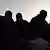 A group of people seen in silhouette, symbolising migrants