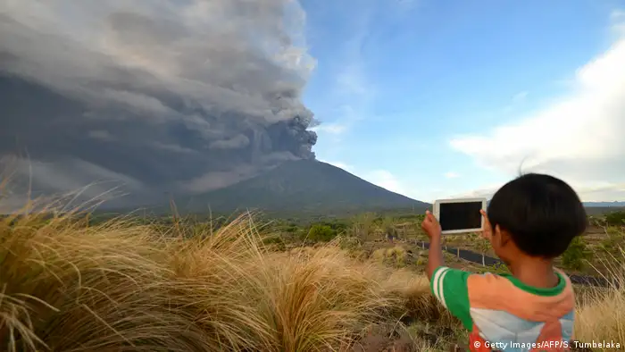 A boy takes a photo of the volcano with a smart phone