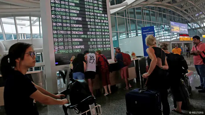 Passengers look at flight schedules at Bali's international airport