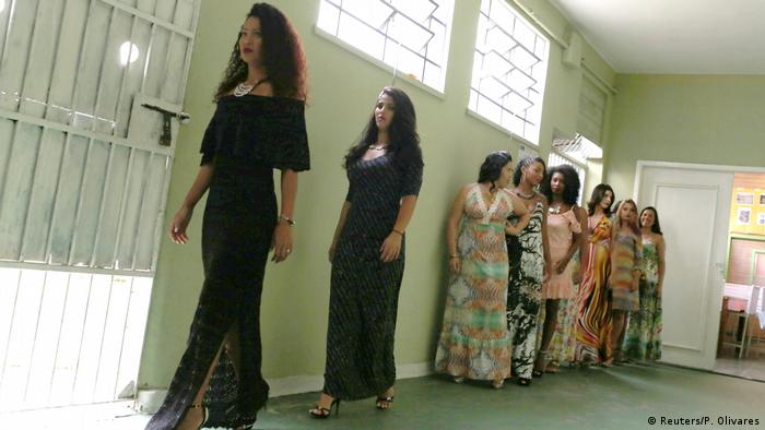 Women, wearing evening dresses, stand in a line waiting to walk in to the contest.