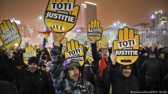 People hold signs that read All for Justice during a protest outside the government headquarters in Bucharest, Romania