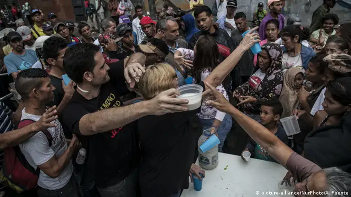 Mneschen drängen sich vor einer Lebensmittelausgabe in Caracas (picture-alliance/NurPhoto/A. Fuente)