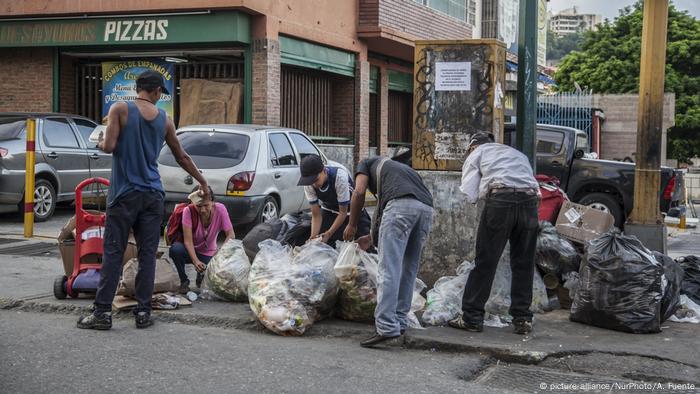 Personas en Caracas, Venezuela, buscan comida en bolsas de basura.