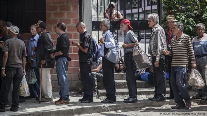 Hombres en Caracas haciendo cola ante una tienda de comestibles