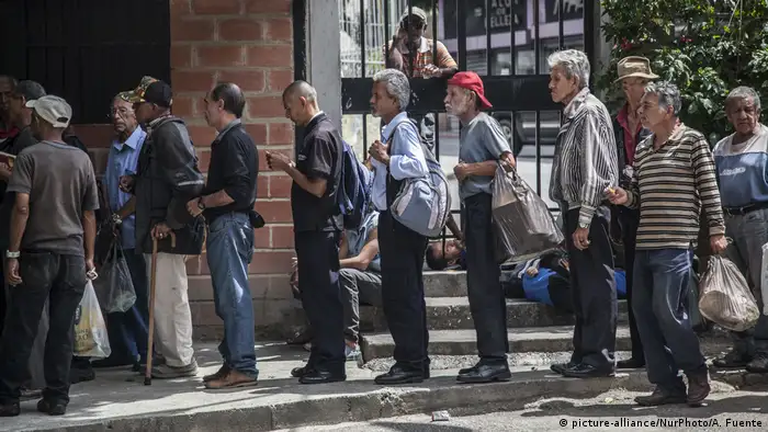 Männer in Caracas stehen Schlange vor einer Lebensmittelausgabe (picture-alliance/NurPhoto/A. Fuente)