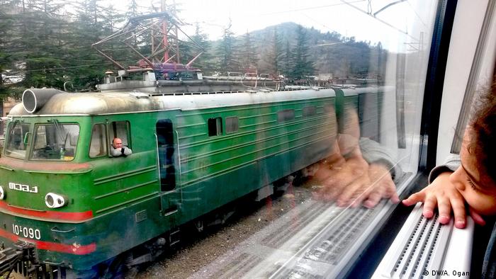 Девочка из окна поезда смотрит на рядом проезжающий другой поезд