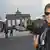 David Hasselhoff in Berlin in glasses pointing to the Brandenburg Gate 