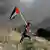 A man runs with a Palestinian flag near the Israeli borde