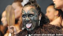 Ein Maori-Mann mit Gesichtsbemalung, der seine Zunge rausstreckt, ein traditioneller Begrüßungsritus der neuseeländischen Ureinwohner (dpa/A. Dedert)