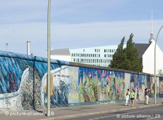 Passanten laufen an einen Rest der Mauer in Berlin entlang (Foto: dpa)