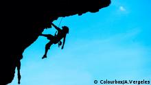 Ein Extremsportler hält sich gesichert durch ein Seil mit bloßen Händen an einem Felsüberhang fest (Quelle: Colourbox/A.Vergeles)