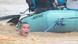 A man clings to the rope of a rescue boat in raging floodwaters. A man clings to the rope of a rescue boat in raging floodwaters.