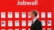 Man walking in front of a wall offering jobs at a technology fair Man walking in front of a wall offering jobs at a technology fair