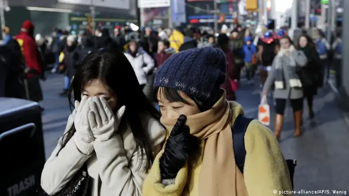 Pedestrians try to keep warm by covering their faces while walking in Times Square, New York