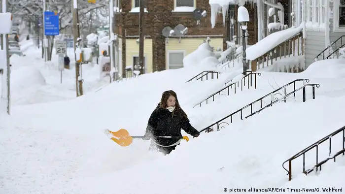 A woman shovels snow from her house entrance