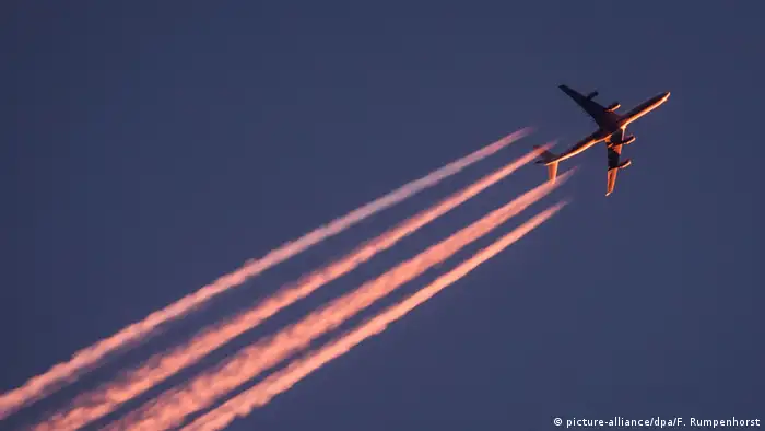 An airplane flies with contrails in its wake