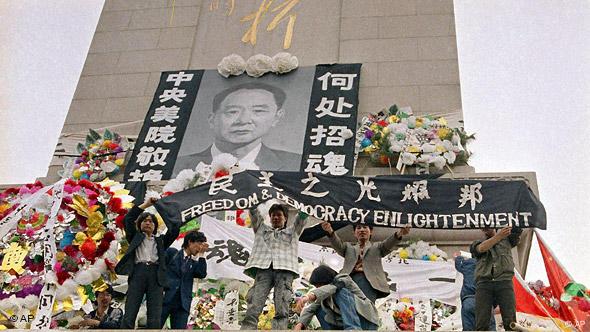 Chinese students hold aloft a banner calling for 'Freedom & Democracy Enlightment' on the martyrs monument in Beijing's Tiananmen Square festooned on Wednesday, April 19, 1990 with a giant portrait of Hu Yaobang. (AP Photo/Mark Avery)