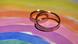 Обручальные кольца на фоне радужного флага Обручальные кольца на фоне радужного флага