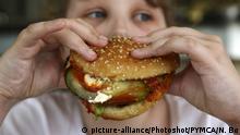 Young boy holds burger with relish in hands |