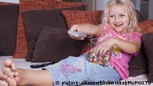 Maedchen mit Suessigkeiten und Fernbedienung beim Fernsehen | girl watching TV with sweeties | Verwendung weltweit
