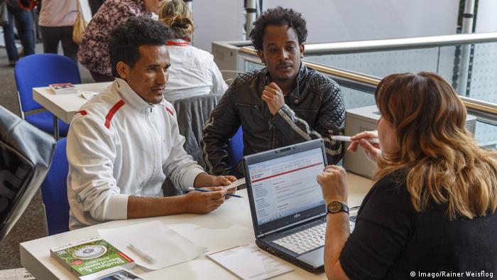 Женщина с ноутбуком и мигранты из Эритреи в Котбусе