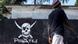 A pirate walks past a pirate banner A pirate walks past a pirate banner