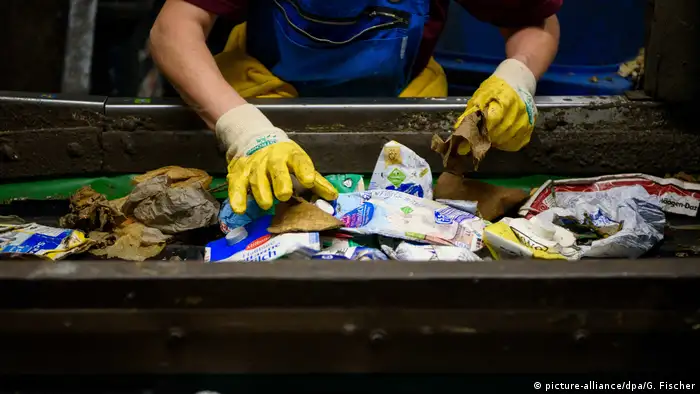 A person sorting packaging waste at a recycling facility