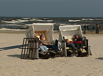 Menschen sitzen am Strand in Strandkörben