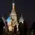 People walk in front of an illuminated St. Basil's Cathedral on Red Square in Moscow