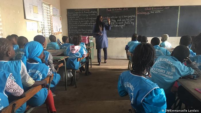 Eine Lehrerin steht vor ihrer Klasse in einer Schule in Dakar, einer Stadt im Senegal. Ihre Schüler folgen aufmerksam den Worten der Lehrerin. DW The 77 Percent Radio