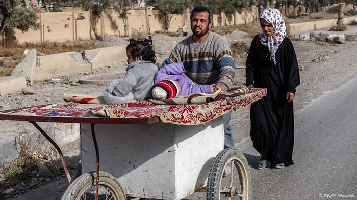 A man in Raqqa pushing a home-made wheelie box
