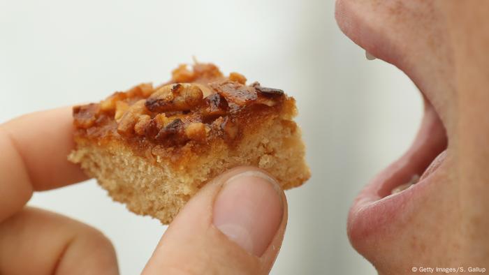 A woman eats a piece of cake with roasted male bees