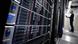A man stands in front of server racks A man stands in front of server racks