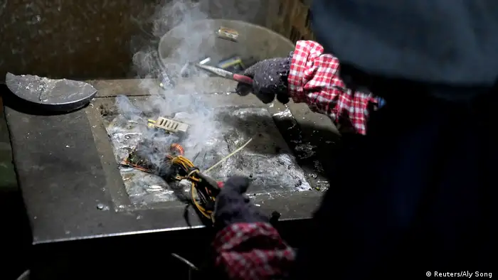 Photo: A worker burns hardware to get to precious metals (Source: Reuters/Aly Song )