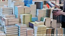 ARCHIV - Eine Frau stapelt Bücher am 16.03.2016 in Vorbereitung auf die Buchmesse in Leipzig (Sachsen). Der deutsche Buchmarkt gilt immer noch als der zweitgrößte der Welt. Doch die Titel-Flut geht weiter zurück. (zu dpa Wer liest denn all die Bücher? - Zahl der Titel nimmt ab) Foto: Jan Woitas/dpa-Zentralbild/dpa +++(c) dpa - Bildfunk+++ | Verwendung weltweit