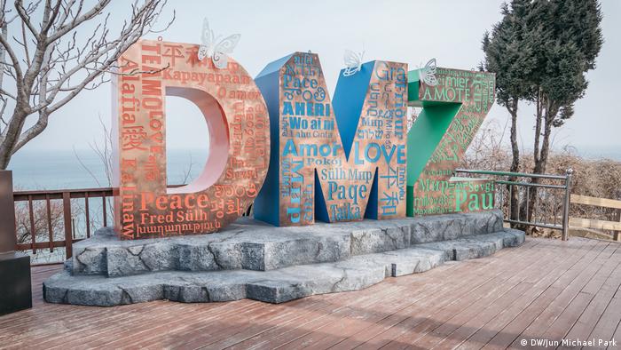 И край платформата за наблюдение от южната страна на вътрешнокорейската граница има мирно послание: върху трите огромни букви DMZ (съкращението на демилитаризирана зона) на различни езици са изписани думите любов и мир. 