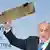 بنیامین نتانیاهو، نخست وزیر اسرائيل، قطعه‌ای را در کنفرانس امنیتی مونیخ نشان می‌دهد که می‌گوید تکه‌ای از پهپاد ایرانی سرنگون‌شده است