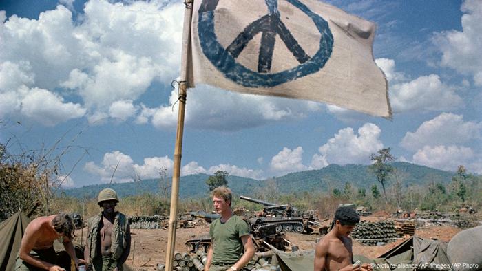 US-Soldaten im Vietnamkrieg neben einer Flagge mit Peace-Zeichen (picture-alliance/AP Images/AP Photo)