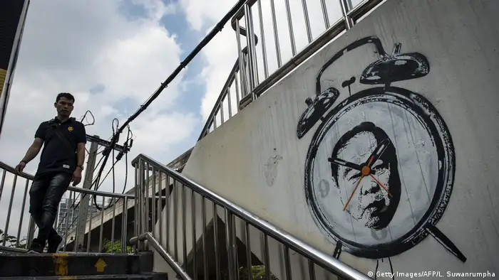Der thailändische Streetart-Künstler Headache Stencil (Kopfschmerz-Schablone) verewigte den General auf einer Fußgängerbrücke in der Hauptstadt Bangkok. Der Wecker zeigt an, dass es Zeit ist, aufzuwachen. Nach einem nächtlichen Besuch der Polizei in seiner Wohnung tauchte der Künstler unter.