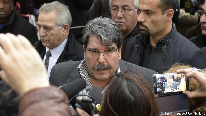 Salih Muslim answers journalists questions at a crowded ceremony in 2015.
