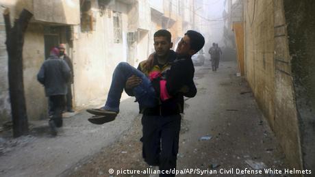 Man carrying wounded man in eastern Ghouta (picture-alliance/dpa/AP/Syrian Civil Defense White Helmets)