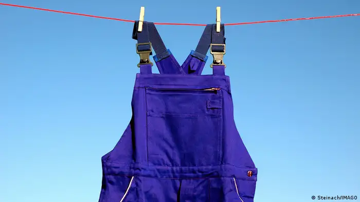 Picture of a pair of purple overalls pegged on a clothesline.
