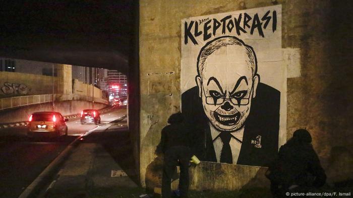 Activist and artist Fahmi Reza (R) and his friend mount a caricature poster depicting Najib with a clown face ahead of a rally in Kuala Lumpur, Malaysia.