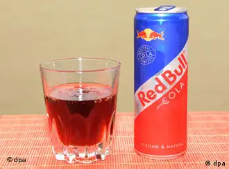 A glass of Red Bull Cola beside a Red Bull Cola can