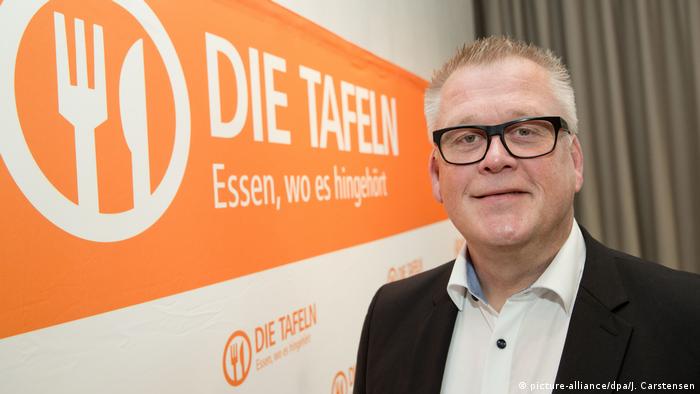 يوخن برول، رئيس مؤسسة تافل، ويظهر خلفه شعار المؤسسة التي هي عبارة عن منظمة جامعة لبنوك الطعام في ألمانيا
