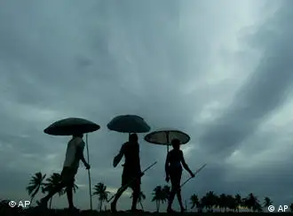 Villagers walk with their umbrellas made of palm leaves as rain clouds loom over the sky in the outskirts of Bhubaneswar, India, Monday, May 25, 2009. Strong winds and heavy rains from Cyclone Aila lashed eastern India and Bangladesh on Monday, killing at least 15 people and stranding thousands in their flooded villages. (AP Photo/Biswaranjan Rout)